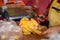 Closeup of a butcher cutting up a chicken with a scissor on a wooden cutting board in the market