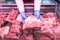 Closeup of butcher`s hands holding meat piece. Offering fresh meat at display in supermarket