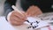 Closeup of calligrapher hands writes phrase on white paper. Inscribing ornamental decorated letters. Calligraphy