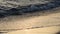 Closeup Calm Waves of the Sea on the Sandy Beach at Sunset. Sun Reflection in Sea Water. Nature background. Evening