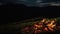 Closeup camp fire burning in dark evening night mountains landscape nature.