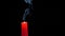 Closeup of candle on black. Someone extinguishes the flame of a red candle with his fingers. 4 k. Slow-motion shooting