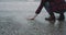 Closeup capturing video of a man beside of a seashore on rain day , he took some wet sand on his hand and throw down