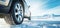 closeup of car wheel with winter tire on snowy mountain landscape background. banner