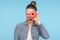 Closeup of carefree amused girl with hair bun peeking through doughnut and sticking out tongue, making face having fun with snack