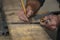 Closeup carpenter marking measurement on wood board with old wooden handle square and pencil