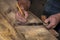 Closeup carpenter marking measurement on wood board with old wooden handle square and pencil