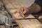 Closeup carpenter marking measurement on wood board with old wooden handle square and pencil