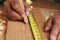 Closeup of a carpenter measuring and marking a board for cutting. Man is unrecognizable, hands only