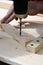 Closeup of a carpenter using metal drill bit to make holes in a wooden oaks plank.