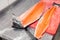 Closeup carving whole fresh norwegian salmon fish with knife on red cutting board in professional kitchen restaurant, preparing