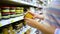 Closeup caucasian woman hands near shop shelves choosing light honey in grocery market