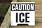 Closeup of a "Caution Ice" sign on the wooden bridge