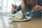 Closeup of cheesecake and leaf of mint sprinkled powder sugar on white plate. Cut view of blonde girl. She holds knife