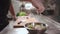 Closeup of chef cook hand in medical gloves put red onion in fresh greek salad