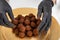 Closeup chef puts pile of dark chocolate truffles in gold dust on golden plate