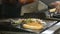 Closeup of a chef tending sandwich meat on a commercial grill