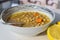 Closeup of chickpea soup on a plate surrounded by lemons on a blurred background