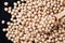 Closeup chickpea in wooden spoon and heap chickpea scattered on the black background
