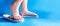 Closeup child feet wearing a pair of fun bright flip-flops on blue background. Kids and family lifestyle outdoors. The concept of