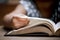 Closeup child hand opening and reading a book in library