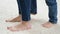 Closeup of child\'s feet beating mother\'s feet standing on white carpet