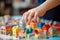 Closeup on child\\\'s hand placing miniature houses among colorful building blocks on a vibrant setup