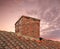 Closeup of a chimney on an old red brick house with copy space sky. Architectural details of an antique steel roof on a