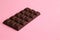 Closeup of a chocolate block placed in a slanted angle on a pink surface