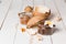 Closeup of chocolate coconut scrub for face and body in small jars with shells and a flower on a white wooden background