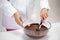 Closeup chocolatier stirs dark melted chocolate in glass bowl white background