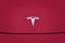 Closeup chromium-plated Logotype Tesla Motors on red hood, most popular passenger electric car in world, Elon Musk, Tesla is an