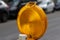 Closeup of a circular yellow warning light in the street with cars in the blurred background