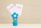 Closeup clamp photo in blue flower shape shape in flowerpot with love you word on white paper on blurred wooden desk and wall back