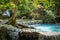 Closeup of a clear pool of water and a short waterfall in Erawan National Park