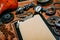 Closeup clipboard with vintage paper in the center of rusty tools, gears on metal background. Motorcycle tools, equipment and