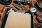 Closeup clipboard with vintage paper in the center of rusty tools, gears on metal background. Motorcycle tools, equipment and