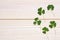 Closeup clovers leaves on white wooden background top view with copy space