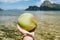 Closeup of coconut in male hands against exotic ocean islands