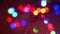 Closeup colorful blinking Christmas garland lights bokeh background surrounded by falling snowflakes