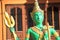 Closeup of colorful green shiva statue with trident in monastery Muang La, Laos