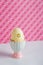 Closeup colorful painted Easter egg in vibrant modern egg stand on spotted pink background