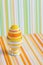 Closeup colorful painted Easter egg in vibrant modern egg stand on striped green and orange background