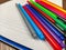 Closeup of colorful pens laying on an empty white notebook for writing down notes as an equipment or supplies for school or