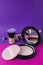 Closeup of compact powder and makeup brushes on the pink purple background.Vertical image