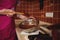 Closeup of a confectioner in pink apron mixing melted chocolate mass in bowl with a wooden spatula