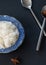 Closeup cooked steam jasmine rice in a blue plat on black background