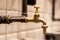 Closeup copper faucet, black industrial pipes on wall with white tiles. Concept designer bathroom in restaraunt, modern interior