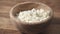 closeup cottage cheese falling into wood bowl