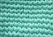 Closeup cotton turquoise knit blanket, warm and comfortable atmosphere. Knit background